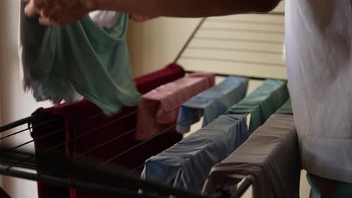 Adult Hanging Laundry on Drying Rack Indoors