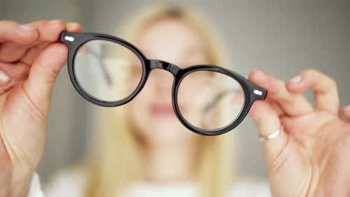Woman holding eyeglasses in her hands.