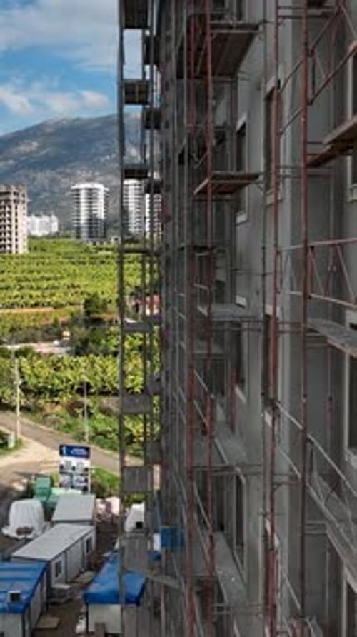 Vídeo vertical: la fachada del progreso de la construcción funciona en andamios, rica infraestructura, colores llamativos