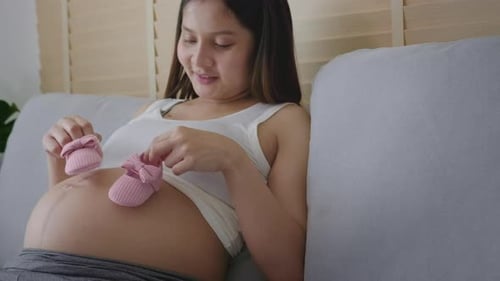 Pregnant Woman with Baby Shoes at Home