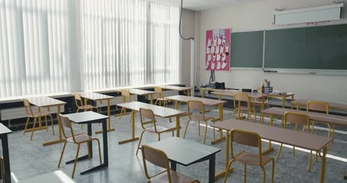 Inside view of a classroom in primary or lower secondary school. Empty classroom with chairs and des