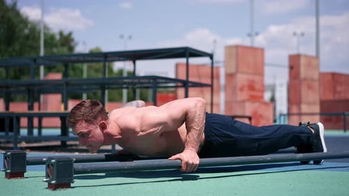 young pumped-up athlete doing push-ups from the ground during street training endurance exercise