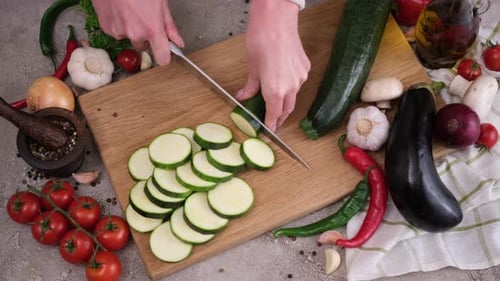 Slicing Fresh Zucchini on Cutting Board with Knife