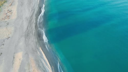 Aerial View of Sandy Beach Meeting Turquoise Sea