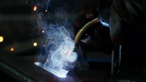 Professional Welder Working at Factory Facility Factory Workshop with a Male Technician Welding in