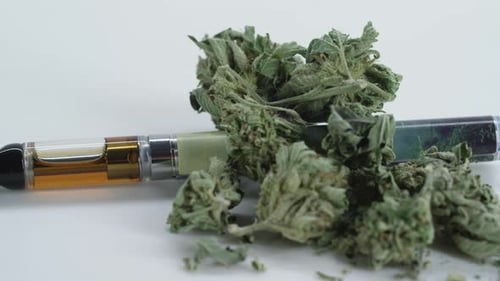 Vape pen next to cannabis flower buds
