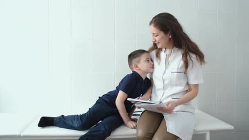 boy at the doctor's office sitting on the couch hugging the doctor