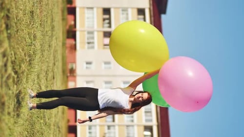 A Girl Happily Poses with Large with Colorful Balloons in the City Vertical Video for Smartphone