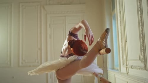 Ballerina Stretching Leg at Barre in Dance Studio