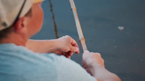 Bamboo rod fishing. Man fishing with retro bamboo fishing rod on the calm river