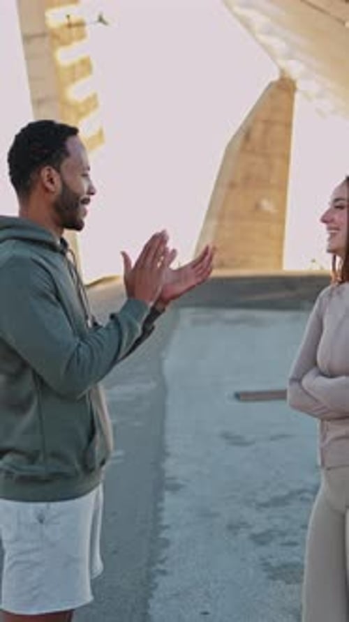 Woman and Man High-Five Outdoors in Urban Setting