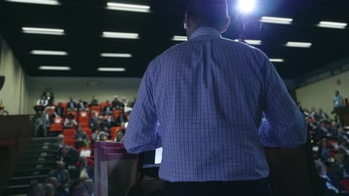 A man holds a speech to the audience in an auditorium on a convention of economics and finance the