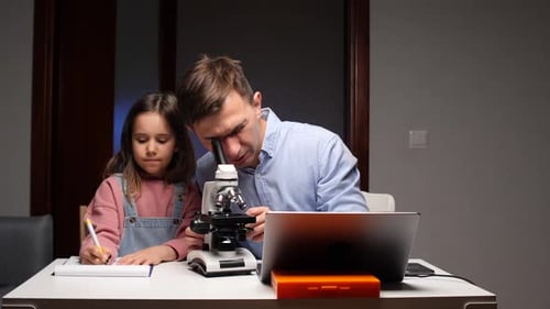 Father and Daughter Studying with a Microscope Indoors