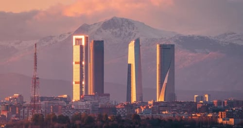Madrid cinco torres skyline and snowy mountains Sierra de Guadarrama during sunset winter day to nig