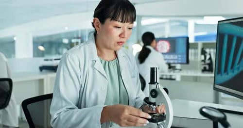 Scientist Examining Sample Under Microscope in Laboratory