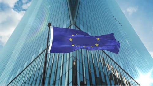European Union Flag Waving in Front of Modern Skyscraper
