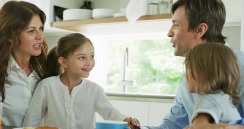 Family Laughing and Talking at Breakfast Table