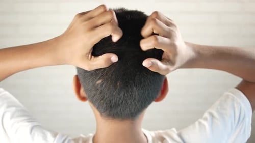 Boy Scratches Head with Both Hands