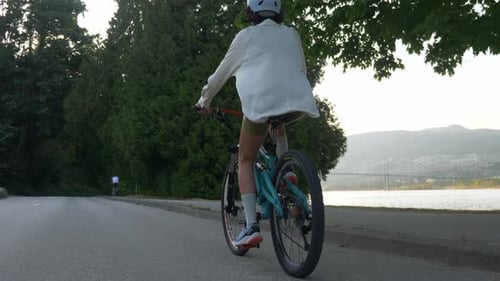 Following A Woman Biking In The Road Along The Burrard Inlet In Vancouver, Canada. - tracking shot