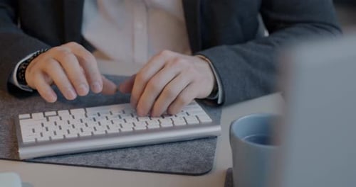 Closeup of Male Hands Typing with Wireless Keyboard While Office Worker Using Personal Computer at