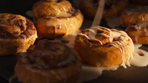 Icing Being Drizzled on Cinnamon Rolls