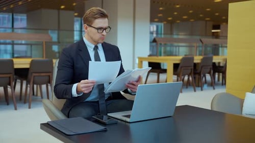 Man in Suit Reads Paperwork in Office Space