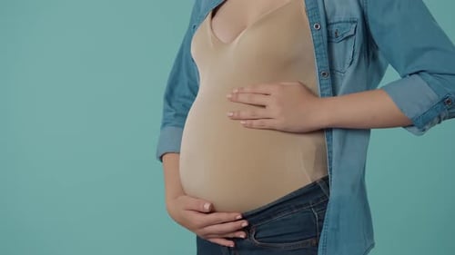 A Pregnant Woman Strokes Her Bloated Stomach with Love and Tenderness Shows a Thumbs Up Bloated