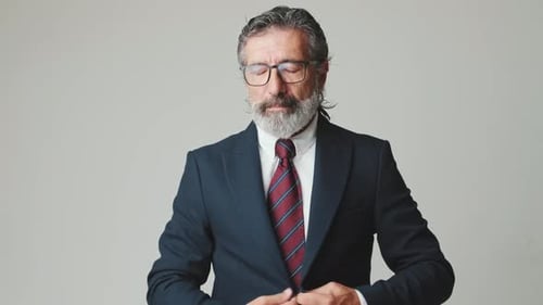 Mature Man Buttoning Suit and Adjusting Tie Indoors