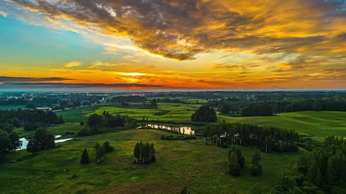 Golden sunset drone hyperlapse over a green countryside and reflective lakes