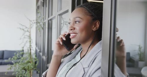 Happy african american casual businesswoman talking on smartphone in office lounge, slow motion