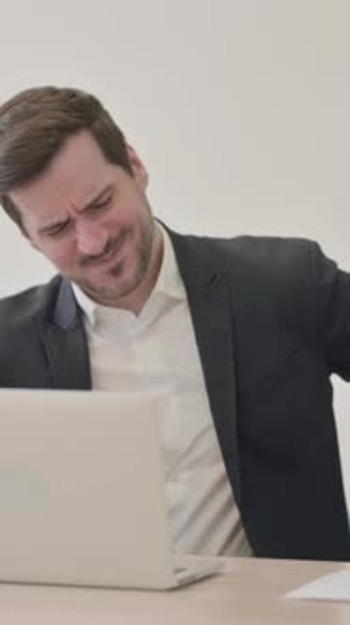 Businessman at Desk Having Back Pain While Working
