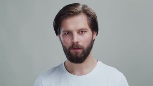 Handsome Young Caucasian Man Wearing Tshirt Looking Into Camera Standing on Grey Isolated Background