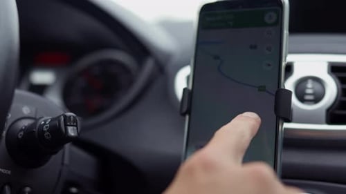 The driver of the car sets up the map of the GPS navigator guide to plot the route. The driver plots