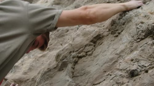 Man Gripping Rock and Climbing Up
