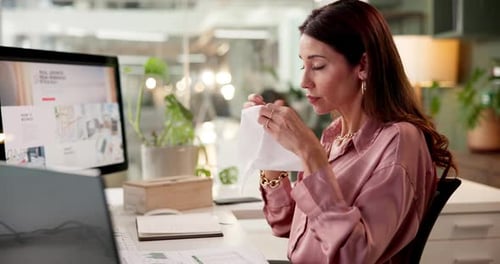 Woman Blowing Nose at Desk in Office