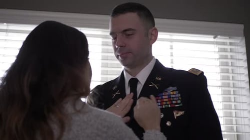 Woman Adjusting Uniform of Man in Military Uniform