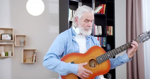 Senior Man Plays Guitar in Living Room