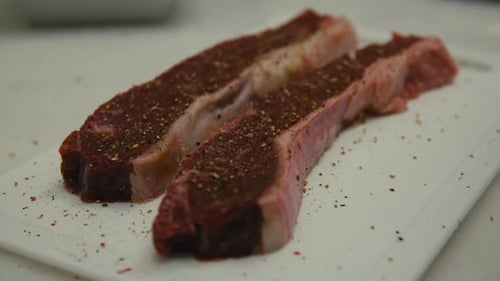 Close-up of seasoned raw entrecôte steak on white cutting board