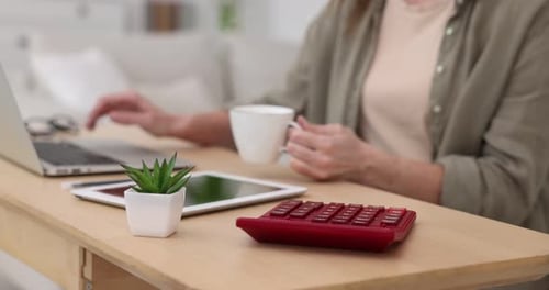Woman Working on Laptop with Calculator at Home