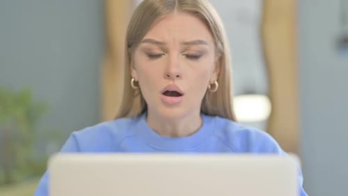 Close Up of Shocked Woman Looking at Camera while using Laptop