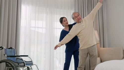 Пожилой мужчина с удовольствием тренируется у физиотерапевта для вытянутых рук дома Asian Physical