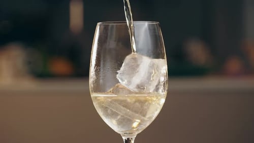 Pouring White Wine Into Glass on Ice Green Spanish Wine on Cafe Background
