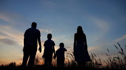 Parents and Kids Silhouettes Raise Hands to Sky at Sunset