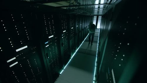 Security Camera Footage of Hacker in a Hoodie Inflitrating Data Center, With His Laptop He Connects