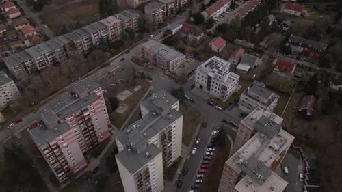 Flying over three residential apartment buildings in the middle of a town.