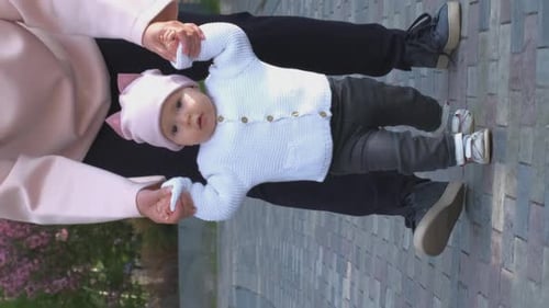 Adorable Baby Learning to Walk Outdoors with Parent