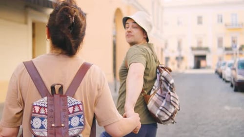 Two Aged Tourists Stand with Their Backs to the Camera Pointing at Landmarks and Discussing the