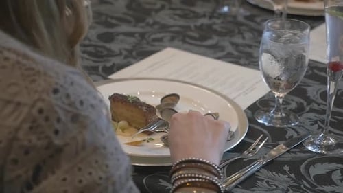 Woman Eating Fish and Oysters at Formal Dining Event