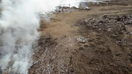 Zeitlupe der Luftaufnahme einer Mülldeponie mit brennenden Müllhaufen