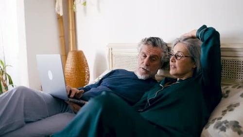 Senior Couple Relaxing in Bed with Laptop